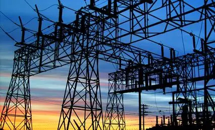 Silhouetted electrical power lines and towers against a colorful sunset sky.