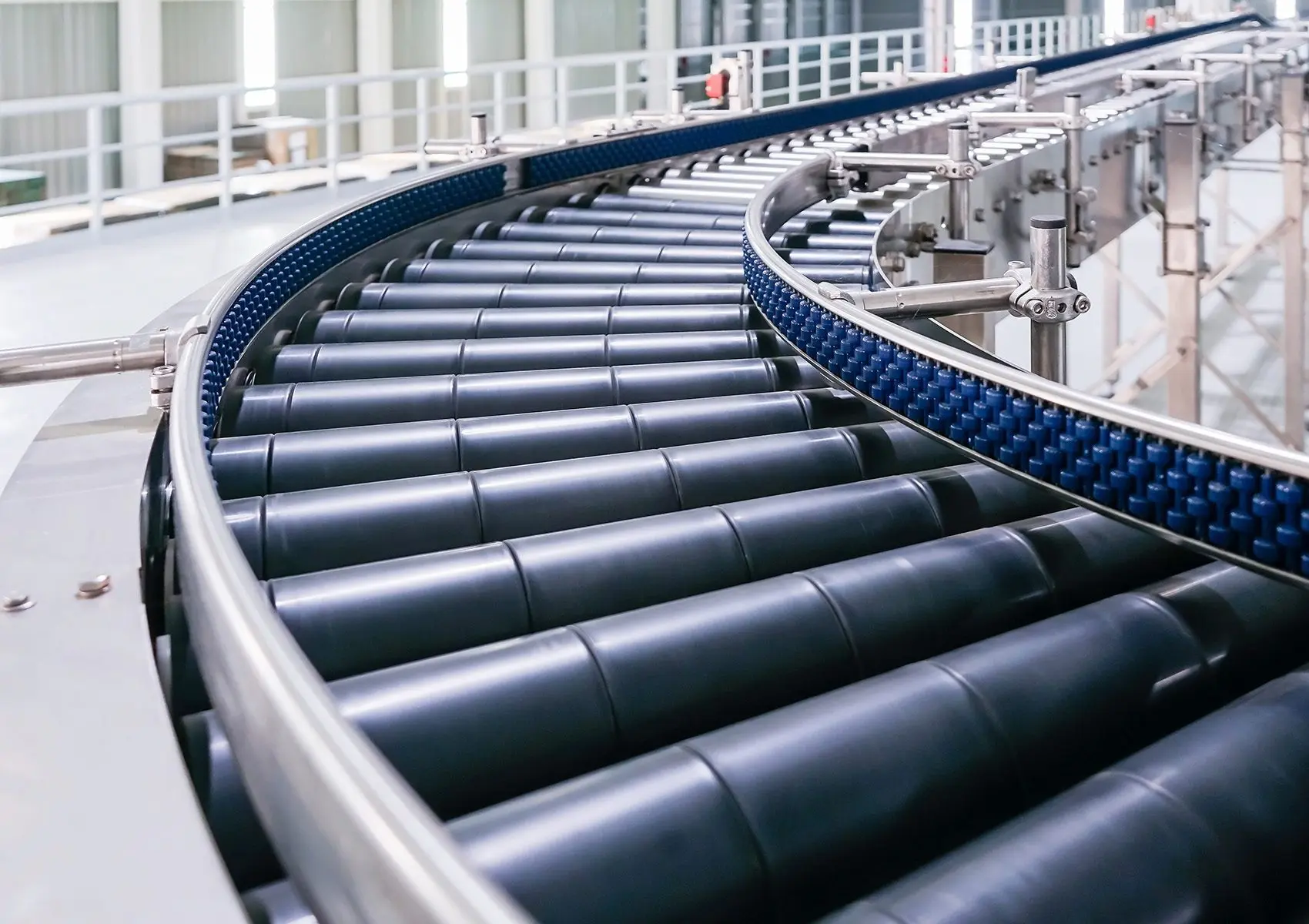 Curved conveyor belt system in a modern industrial facility with black rollers and metal rails.