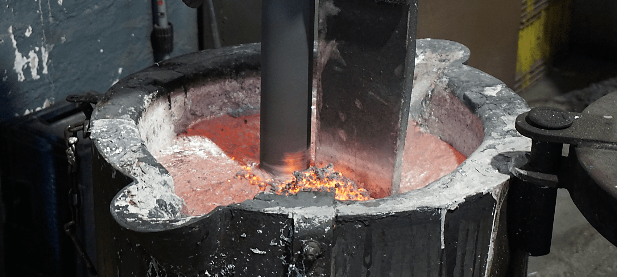 Molten metal being stirred in a crucible furnace during a metalworking process.