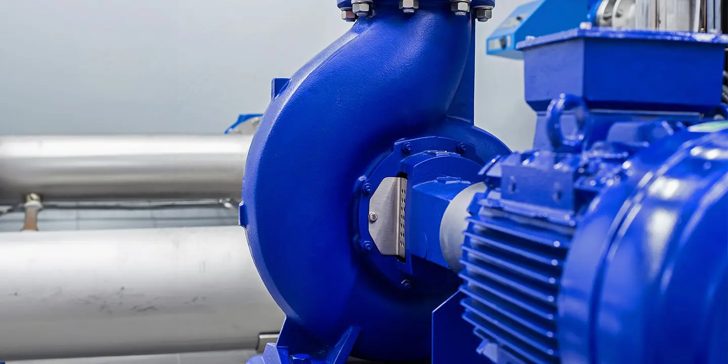 Close-up of a blue industrial centrifugal pump with metal pipes in the background.