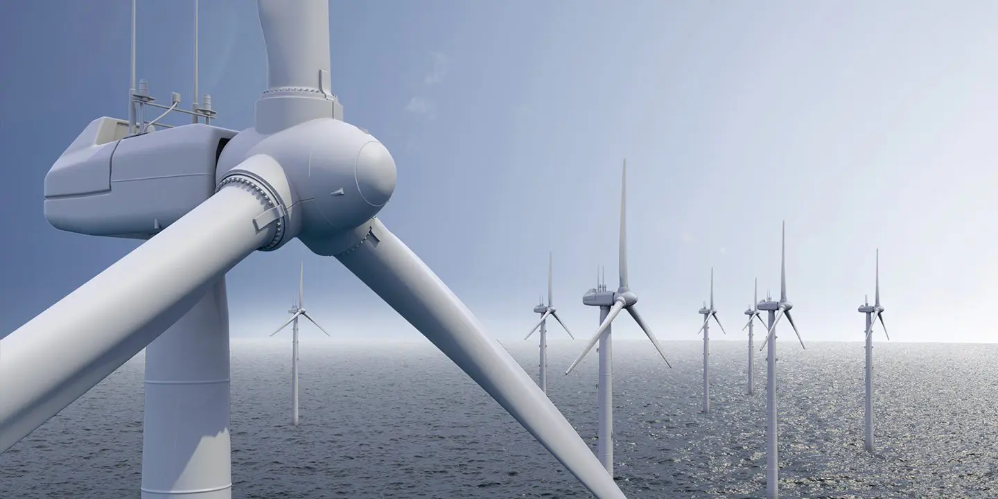 Close-up of offshore wind turbines generating renewable energy over the ocean under a clear sky.