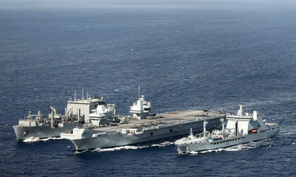 Three naval ships sail side by side on the open sea during a replenishment operation.