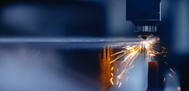 Blue,Color,Laser,Cnc,Cut,Of,Metal,With,Light,Spark, A laser cutting machine emits sparks while slicing through a sheet of metal in a factory setting.