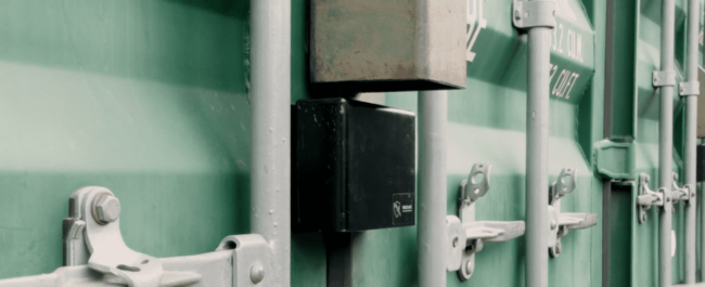 Nov 3 2021 Close-up of locked green shipping container doors with metal handles and latch mechanisms.