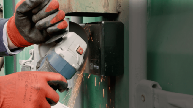 Aug 01 2022 Person wearing gloves uses an angle grinder to cut a metal lock, sparks flying from the tool.