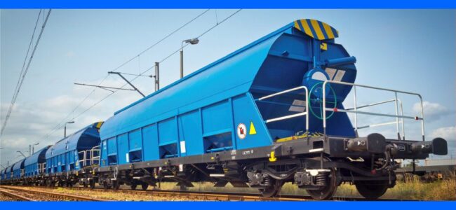 specification-leasing-company-wascosa-railko-products Bright blue freight train cars on railway tracks under a partly cloudy sky, viewed from a low angle.