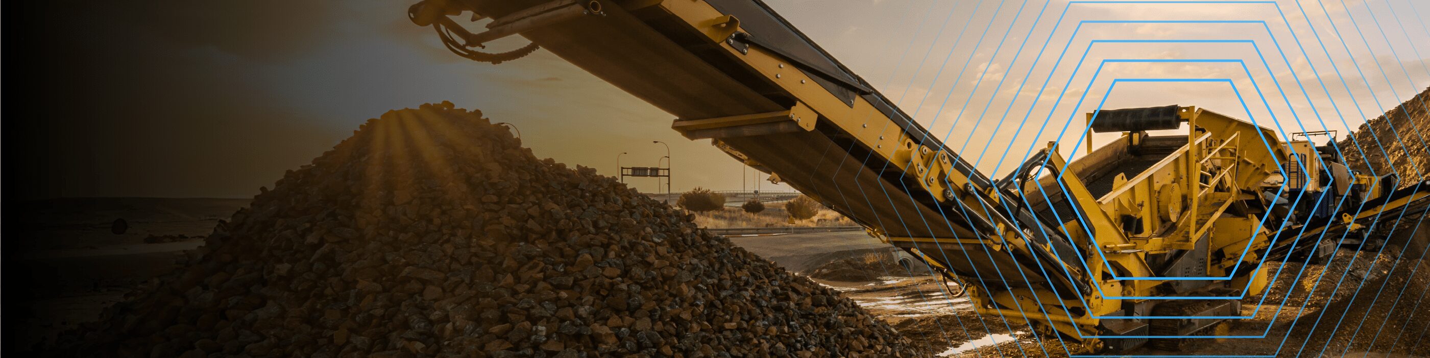 A conveyor belt deposits rocks onto a pile at a mining or construction site under a partly cloudy sky.