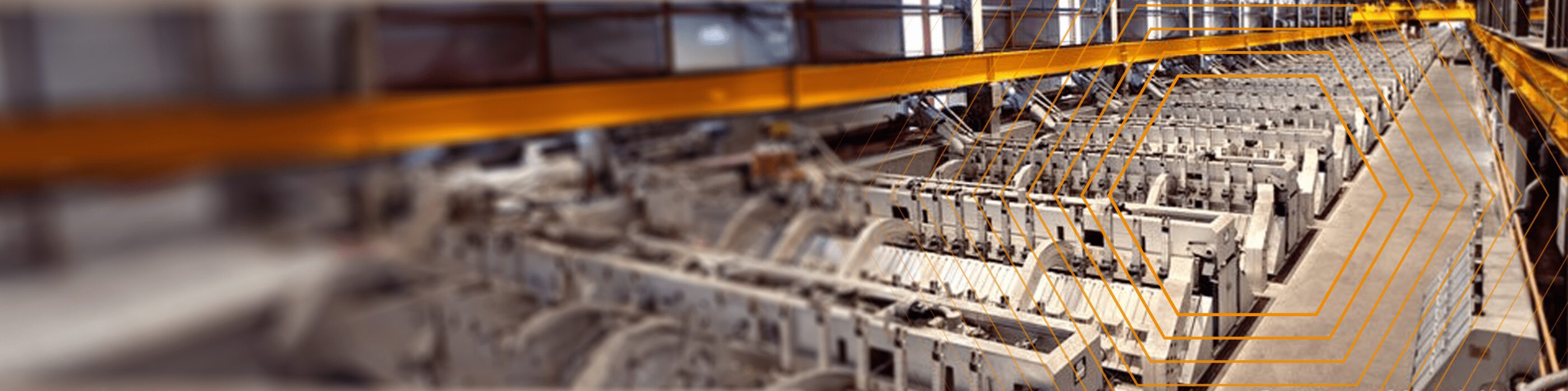 A large industrial facility with rows of metal machinery and overhead yellow cranes.
