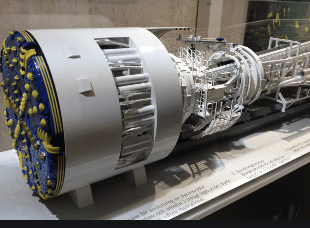A detailed scale model of a tunnel boring machine is displayed behind glass on a white platform.