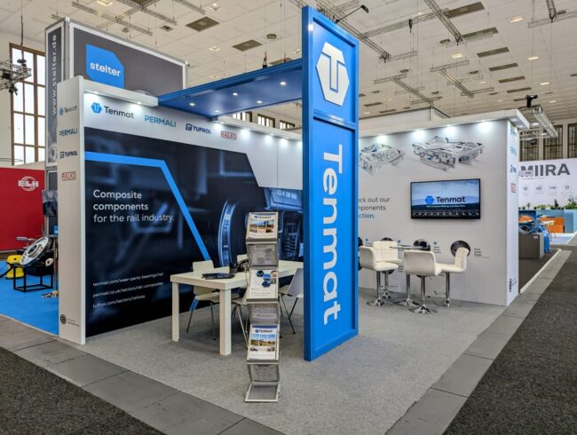 Innotrans Tenmat exhibition booth with banners, brochures, and a screen at a trade show event.