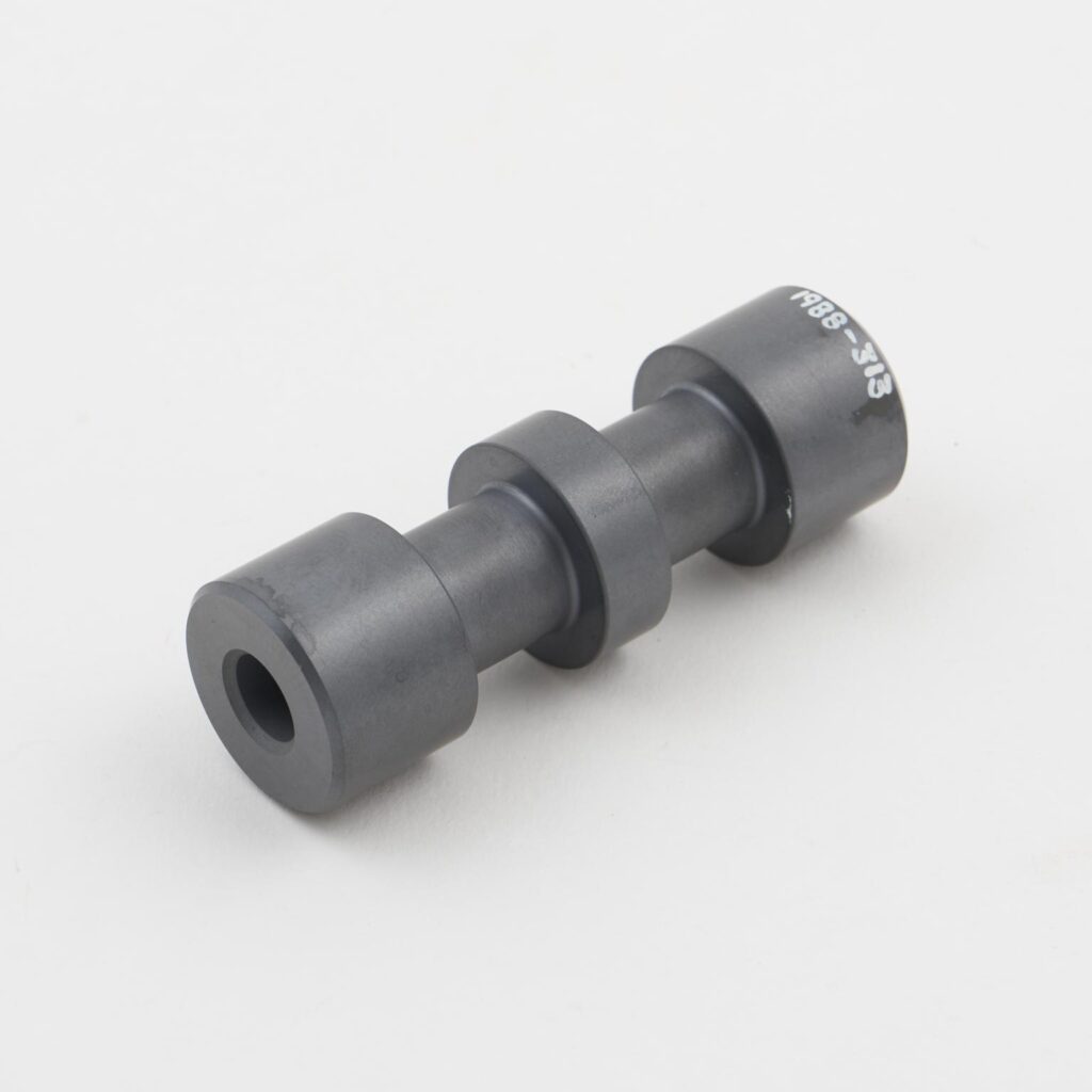 Cylindrical black composite or polymer component with stepped sections and a central bore, shown on a plain light background.