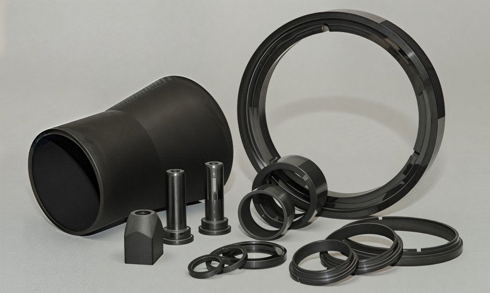 Black machined plastic or rubber industrial components arranged on a light gray surface.